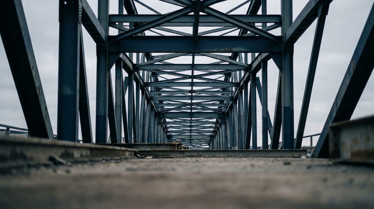 The intersecting steel structure beneath a large bridge seen from below, representing the layered legal and governance systems underneath a cross-border investment