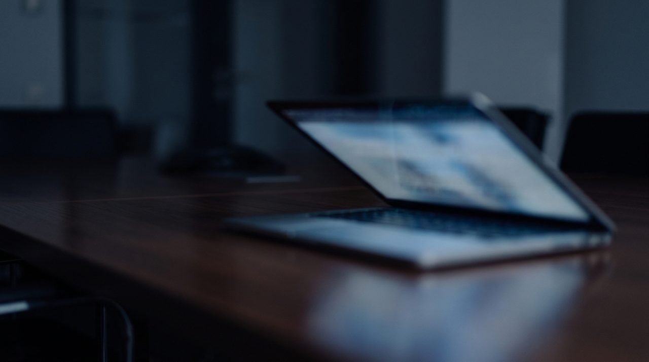 Soft laptop screen glow reflected on a dark desk surface
